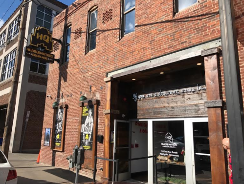 Exterior of a brick building with a sign reading "HQ Headquarters" and a welcoming entrance.