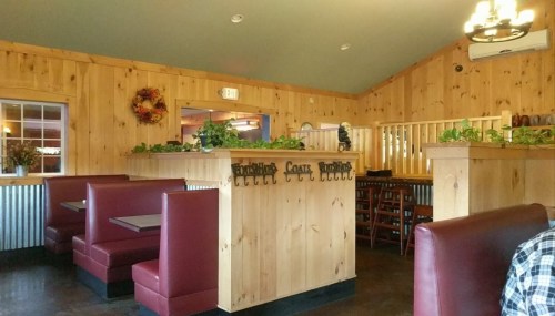Cozy restaurant interior with wooden walls, red booths, and greenery, featuring a warm, inviting atmosphere.