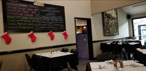 Interior of a restaurant featuring tables, a chalkboard menu, and festive decorations.