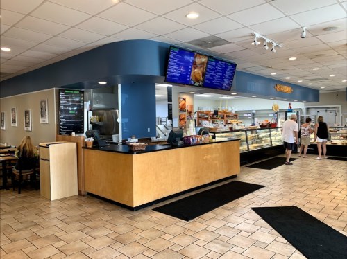 A bright café interior with a service counter, display cases, and customers ordering at the counter.
