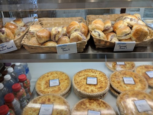 Baskets of rolls and pies displayed in a glass case, with labels for ham and sausage biscuits.