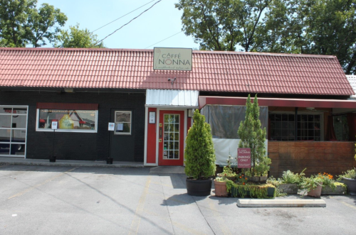 Exterior of Caffè Nonna, featuring a red roof, large windows, and potted plants in front.