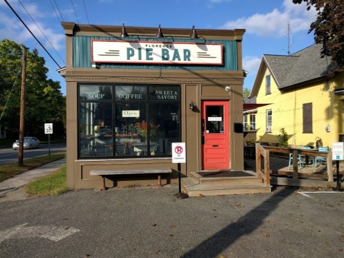 A quaint pie bar with a colorful sign, featuring outdoor seating and a welcoming entrance.