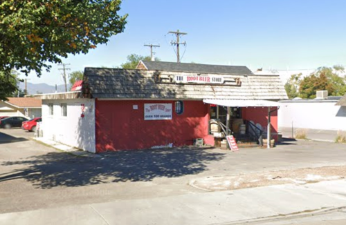 A red building with a sloped roof and a sign reading "The Door Bell Store," surrounded by trees and parked cars.