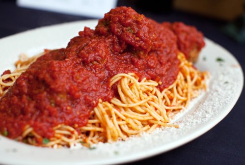 A plate of spaghetti topped with meatballs and marinara sauce, garnished with parsley.