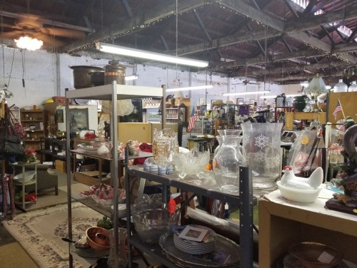A vintage shop interior filled with various items, including glassware, decorations, and shelves of collectibles.