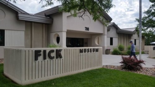 Exterior view of the Fick Museum, featuring a modern building with a landscaped entrance and a visitor walking by.