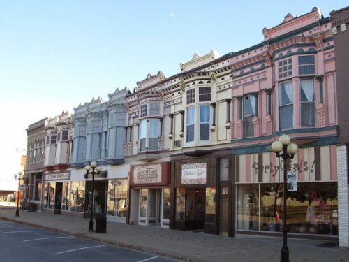 Colorful historic buildings line a street, showcasing ornate architecture and storefronts in a charming small town.