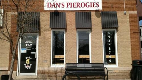 Exterior of Dan's Pierogies restaurant, featuring large windows, a sign, and a bench outside.
