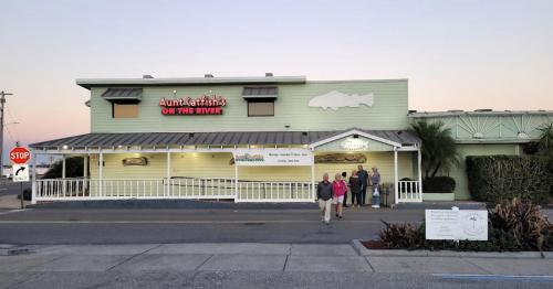 Aunt Catfish's on the River restaurant exterior at dusk, with a group of people standing in front.