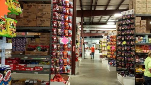A spacious warehouse filled with colorful candy displays and shelves stocked with various snacks and treats.