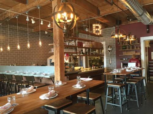 Cozy restaurant interior with wooden beams, industrial lighting, and a mix of tables and bar seating.