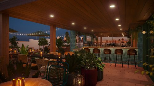 A cozy rooftop bar at night, featuring plants, warm lighting, and a view of the city skyline.
