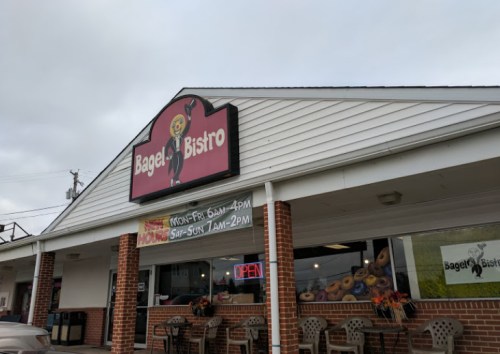 A storefront of Bagel Bistro with a sign, open hours displayed, and a welcoming atmosphere.