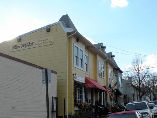 A yellow building with a sign for a restaurant and wine bar, featuring festive decorations and nearby parked cars.