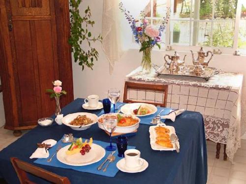 A beautifully set dining table with a blue tablecloth, featuring various dishes, drinks, and floral arrangements.