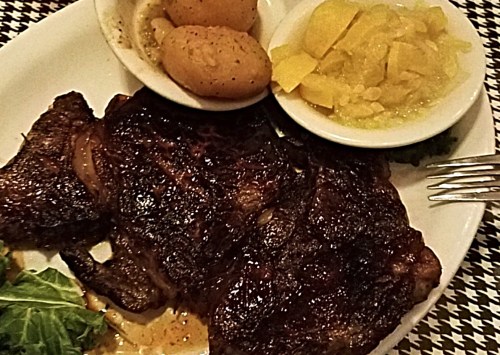 A plate featuring grilled meat, seasoned potatoes, and a side of pickled vegetables.
