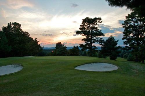A serene golf course at sunset, featuring sand traps and trees against a colorful sky.