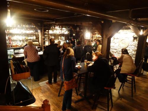 A cozy bar scene with patrons socializing, a well-stocked shelf of drinks, and warm lighting creating an inviting atmosphere.