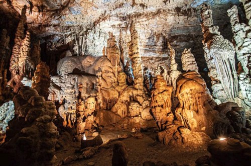 A stunning cave interior featuring intricate stalactites and stalagmites illuminated by soft lighting.