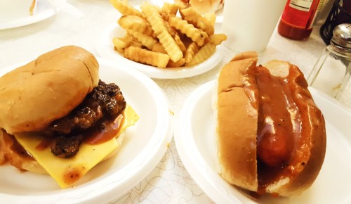 A plate with a cheeseburger and a hot dog, accompanied by a side of crinkle-cut fries.