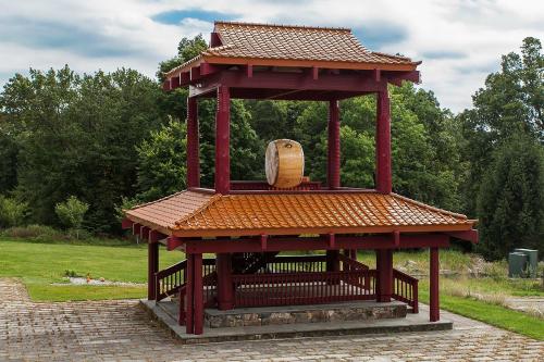 A traditional Asian-style pavilion with a large drum, surrounded by greenery and a stone pathway.