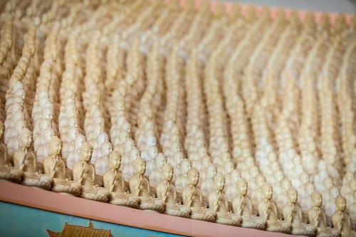A close-up of numerous small Buddha statues arranged in rows, creating a serene and repetitive pattern.