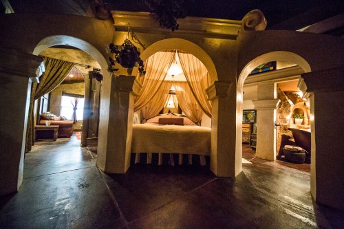 Cozy bedroom with arches, draped curtains, and warm lighting, creating an inviting and intimate atmosphere.