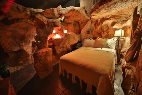 Cozy bedroom with a rock cave theme, featuring a bed, soft lighting, and natural stone walls.