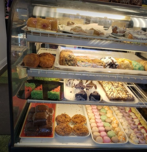 A display case filled with various baked goods, including cookies, pastries, and colorful desserts.