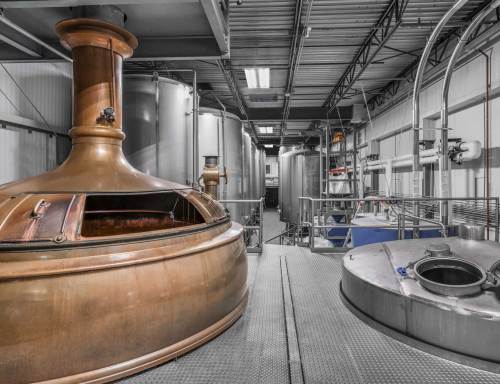 Interior of a brewery featuring large copper and stainless steel fermentation tanks.