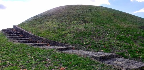 A grassy hill with stone steps leading up one side, under a bright sky.