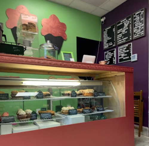 A colorful bakery display with various pastries and a menu board on the wall in a cozy shop setting.