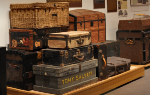 A collection of vintage trunks and suitcases displayed in a museum setting.