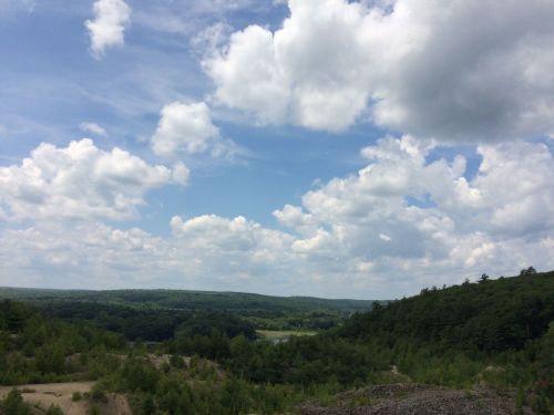A scenic view of rolling green hills under a blue sky filled with fluffy white clouds.