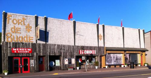 Historic building with "Fort de Buade" sign, featuring a museum, gallery, and shops, under a clear blue sky.