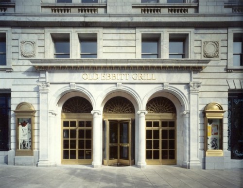 Exterior of Old Ebbitt Grill, featuring a grand entrance with arched windows and gold lettering on a stone facade.