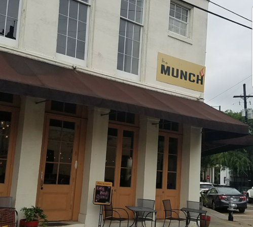 Exterior of "The Munch" restaurant, featuring a sign, awning, and outdoor seating area.