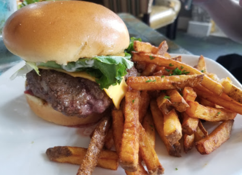 A juicy cheeseburger with lettuce on a bun, served with a side of crispy golden fries.