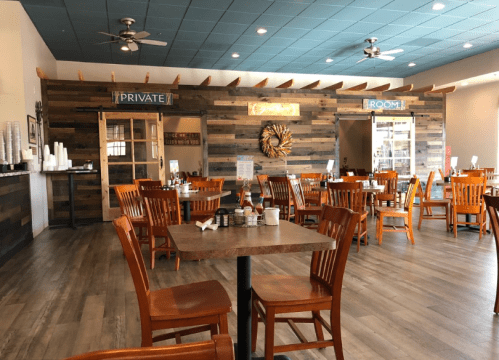 Interior of a restaurant featuring wooden decor, tables, chairs, and signs for a private room. Bright and inviting atmosphere.