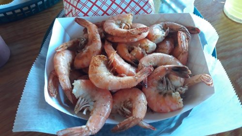 A basket of cooked shrimp, seasoned and arranged neatly on a paper-lined tray.