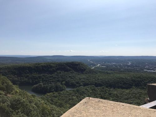A panoramic view of lush green hills and a winding river under a clear blue sky.