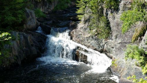 A serene waterfall cascading over rocky terrain, surrounded by lush greenery and trees.