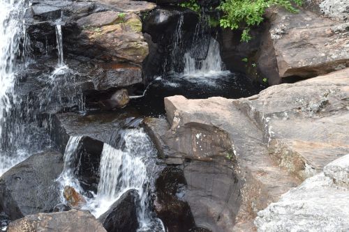 A serene waterfall cascading over rocky terrain, surrounded by lush greenery.