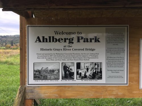 Sign welcoming visitors to Ahlberg Park at the Historic Grays River Covered Bridge, featuring historical images and information.