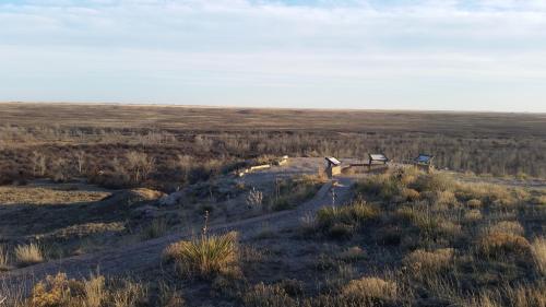 A scenic view of a flat landscape with a walking path and informational signs on a hill, under a clear sky.