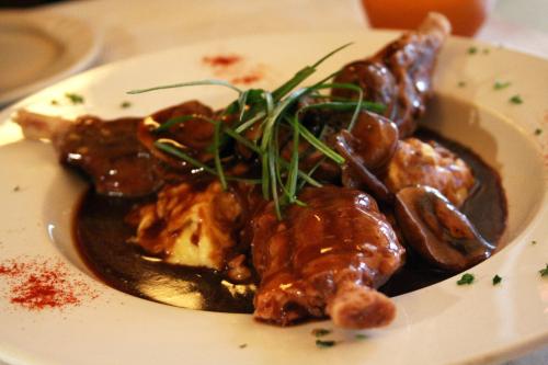 A plate of tender meat with a rich sauce, garnished with green herbs and served over creamy mashed potatoes.