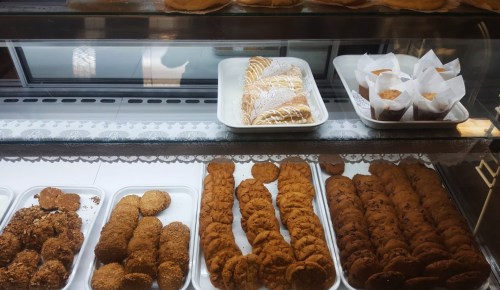 A display case filled with various baked goods, including cookies and pastries, arranged on white trays.