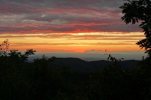 A vibrant sunset over rolling mountains, with colorful clouds and a serene landscape in the foreground.