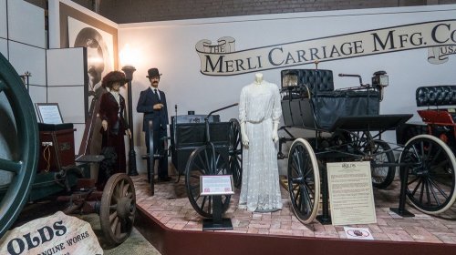 A vintage display featuring a horse-drawn carriage, historical figures in period attire, and a white dress.